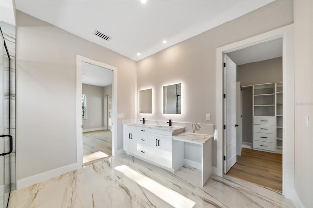 bathroom with marble finish floor, double vanity, visible vents, a spacious closet, and baseboards