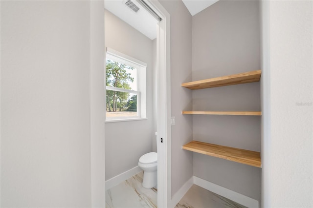 bathroom with toilet, visible vents, and baseboards