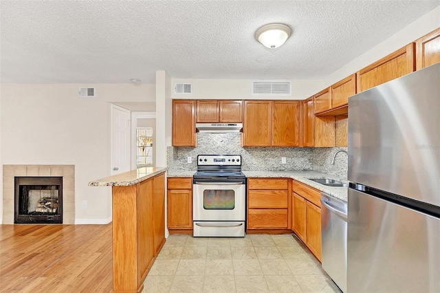 kitchen featuring stainless steel appliances, a sink, visible vents, and under cabinet range hood