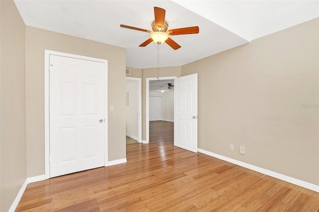 unfurnished bedroom with ceiling fan, light wood-style flooring, and baseboards