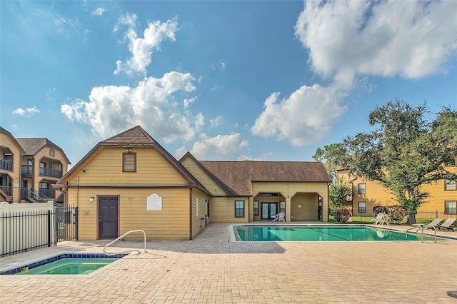 community pool with a community hot tub, a patio, and fence