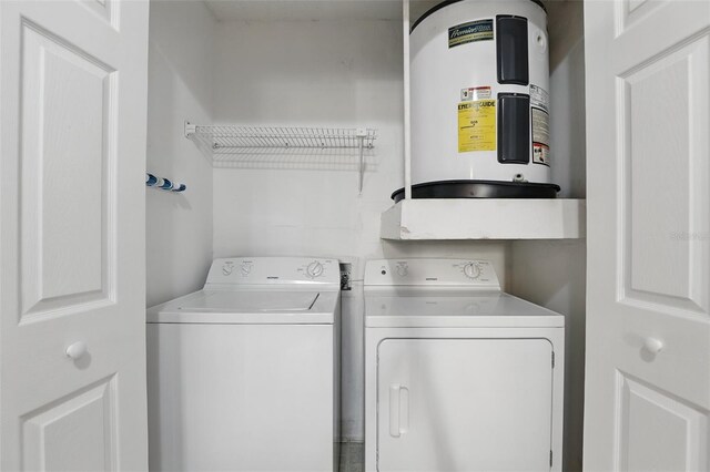 washroom with laundry area, washing machine and clothes dryer, and electric water heater