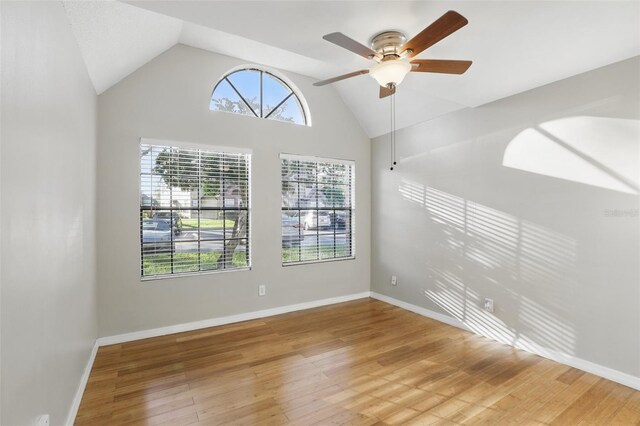 unfurnished room featuring a ceiling fan, high vaulted ceiling, baseboards, and wood finished floors