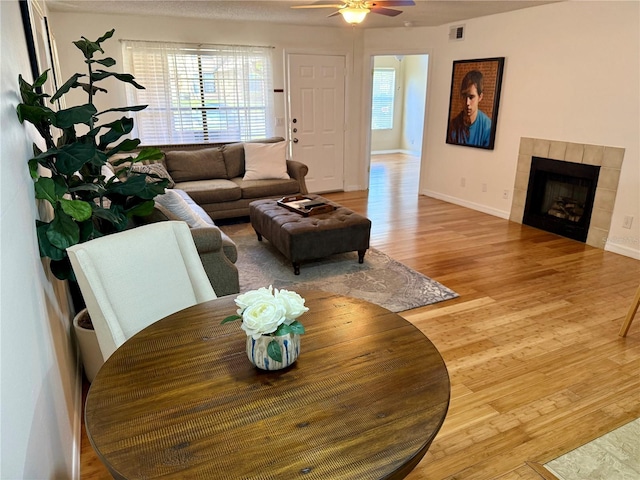 living room featuring light wood-style floors, baseboards, a fireplace, and visible vents