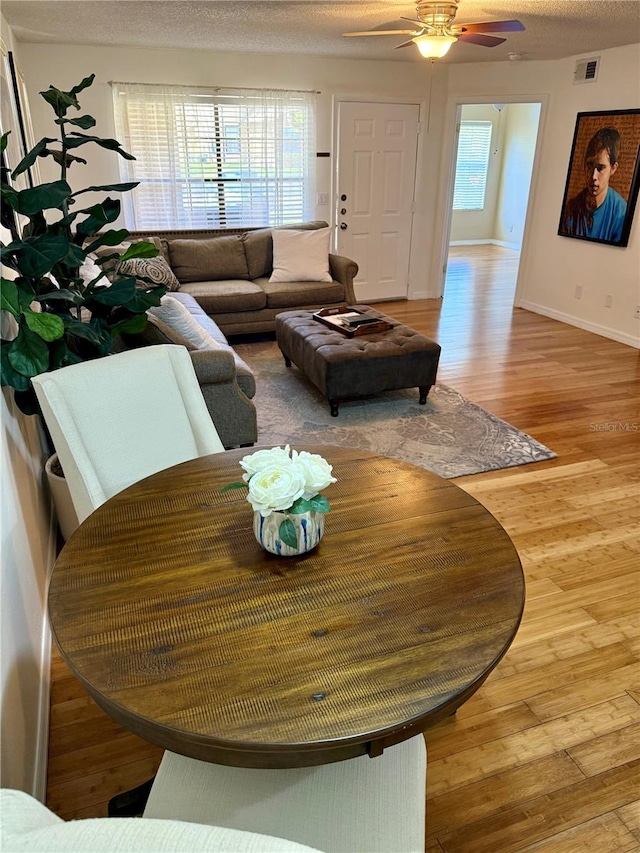 dining space with a healthy amount of sunlight, a textured ceiling, visible vents, and wood finished floors