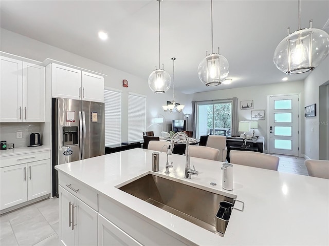 kitchen featuring white cabinetry, sink, pendant lighting, and stainless steel fridge