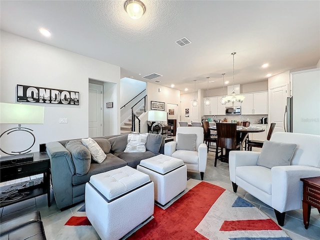 tiled living room featuring a textured ceiling and a notable chandelier