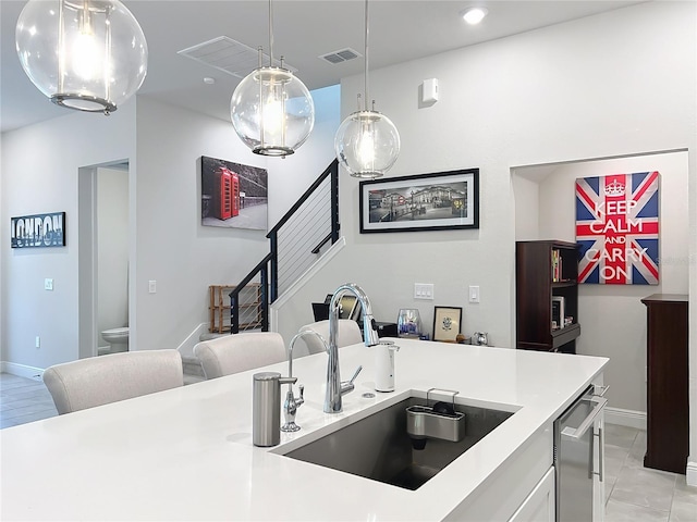 kitchen with white cabinetry, decorative light fixtures, dishwasher, and sink