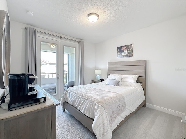 carpeted bedroom with french doors, a textured ceiling, and access to outside