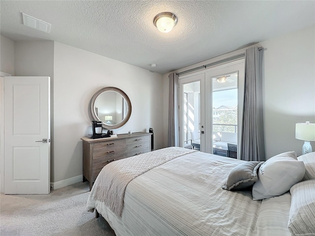 carpeted bedroom with access to outside, french doors, and a textured ceiling