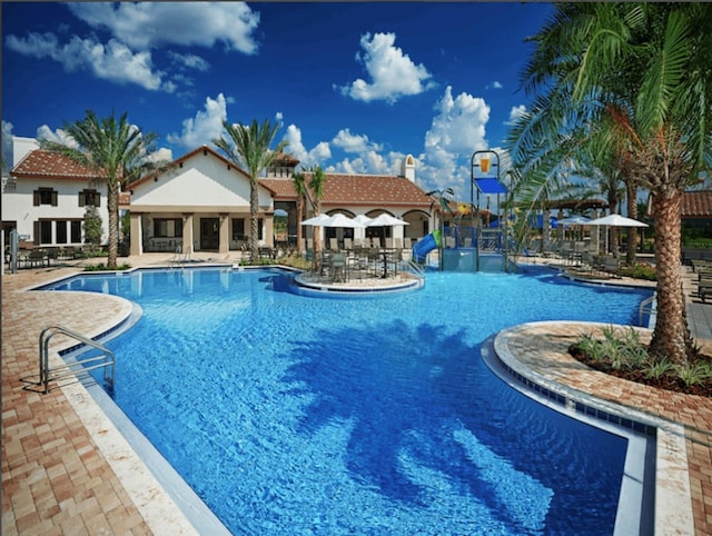 view of swimming pool featuring a water slide and a patio