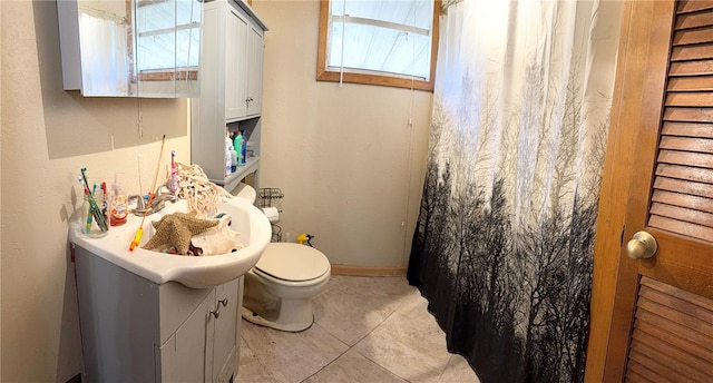 bathroom featuring toilet, tile patterned flooring, vanity, and a healthy amount of sunlight