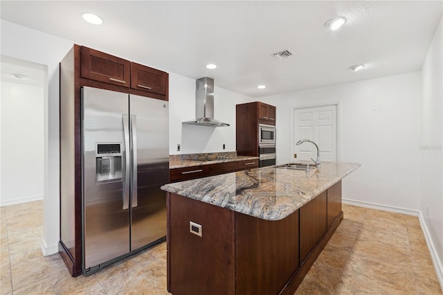 kitchen featuring stone counters, sink, a kitchen island with sink, stainless steel appliances, and wall chimney exhaust hood