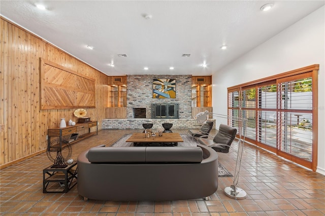 living room with a brick fireplace and wood walls