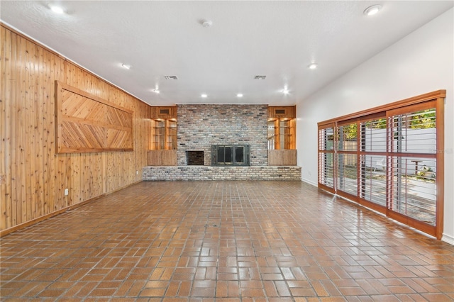 unfurnished living room with wooden walls and a brick fireplace