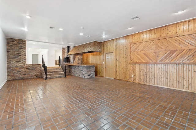 unfurnished living room featuring wooden walls