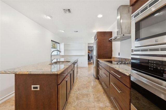 kitchen featuring sink, appliances with stainless steel finishes, a kitchen island with sink, range hood, and light stone counters