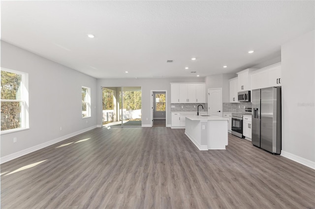 kitchen featuring sink, white cabinetry, an island with sink, wood-type flooring, and appliances with stainless steel finishes