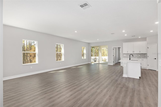 unfurnished living room with hardwood / wood-style floors, a healthy amount of sunlight, and sink