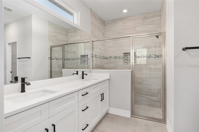 bathroom with a shower with door, tile patterned floors, and vanity