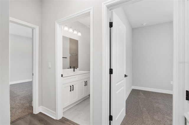 hallway featuring sink and light colored carpet