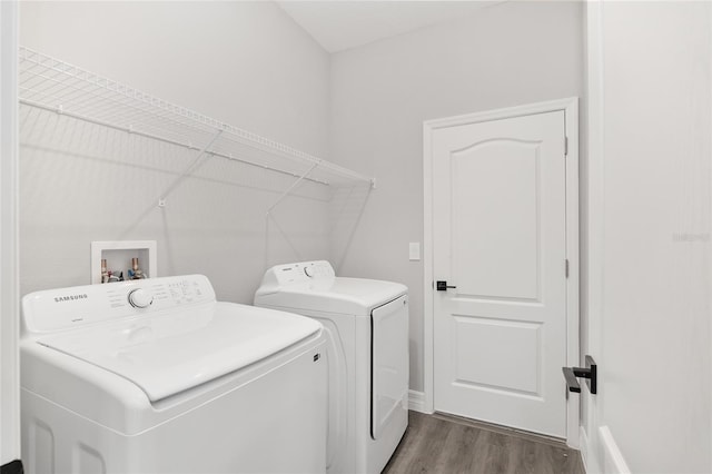 clothes washing area with separate washer and dryer and dark wood-type flooring