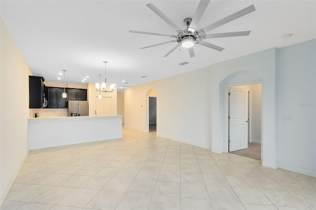 unfurnished living room with ceiling fan with notable chandelier and light tile patterned floors