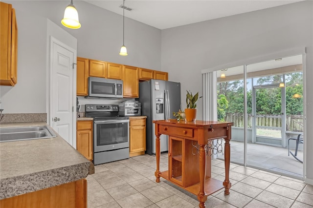 kitchen with stainless steel appliances, decorative light fixtures, light tile patterned flooring, and sink