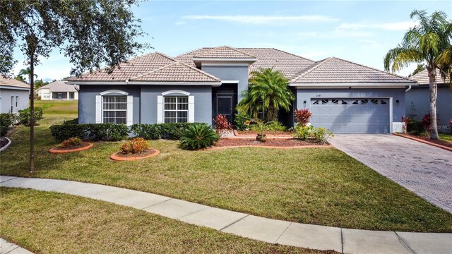 mediterranean / spanish-style home featuring a front yard and a garage