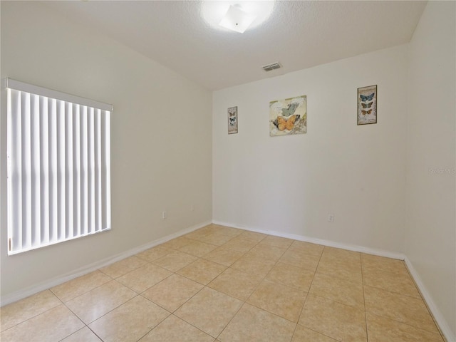 tiled empty room with a textured ceiling