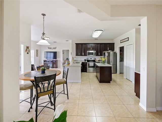 kitchen with stainless steel appliances, a center island, light tile patterned flooring, dark brown cabinets, and pendant lighting