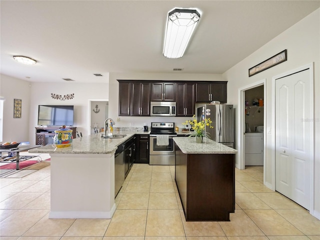 kitchen featuring stainless steel appliances, sink, light tile patterned flooring, kitchen peninsula, and light stone countertops