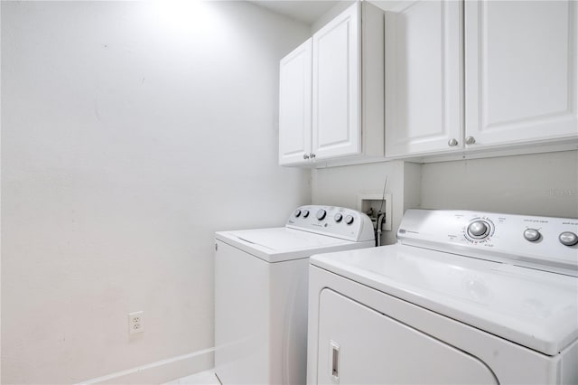 clothes washing area featuring cabinets and washer and clothes dryer