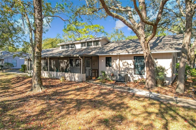 view of front of home featuring a front yard, a sunroom, and central AC unit