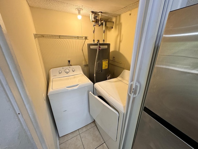 laundry area with electric water heater, washing machine and clothes dryer, and light tile patterned floors