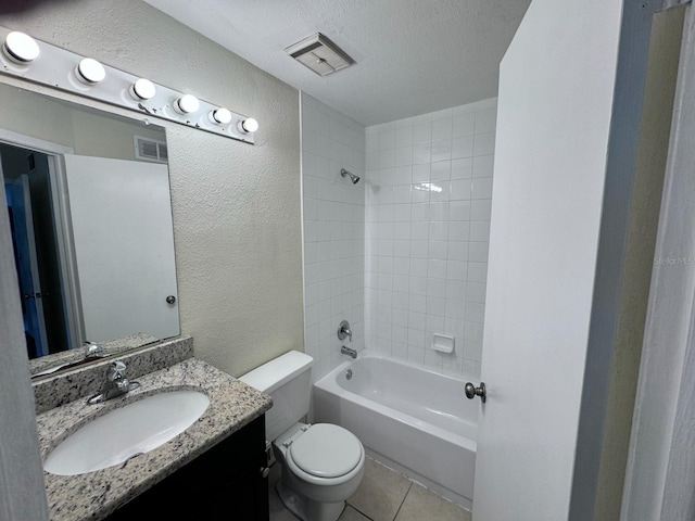 full bathroom with toilet, tile patterned floors, vanity, tiled shower / bath, and a textured ceiling