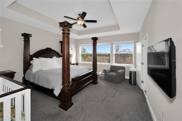 carpeted bedroom featuring ceiling fan and a tray ceiling