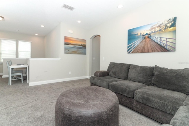 carpeted living room with baseboards, visible vents, arched walkways, and recessed lighting