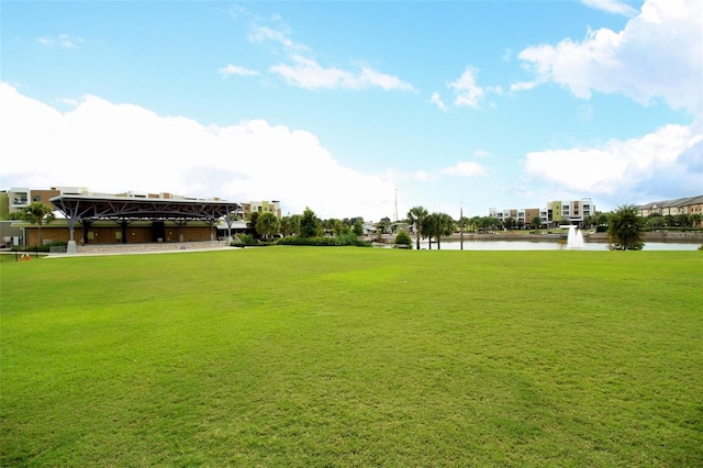 surrounding community with a water view and a yard