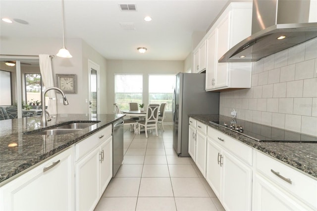 kitchen with stainless steel appliances, a sink, white cabinetry, visible vents, and wall chimney exhaust hood