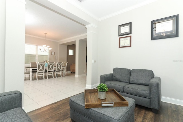 living room featuring wood finished floors, crown molding, baseboards, and decorative columns