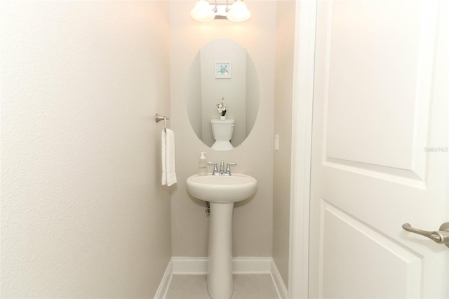 bathroom featuring toilet, a notable chandelier, a sink, baseboards, and tile patterned floors