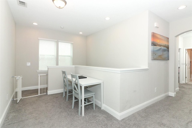 unfurnished office featuring recessed lighting, visible vents, arched walkways, and light colored carpet