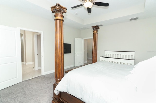 bedroom with light colored carpet, a tray ceiling, visible vents, and a ceiling fan