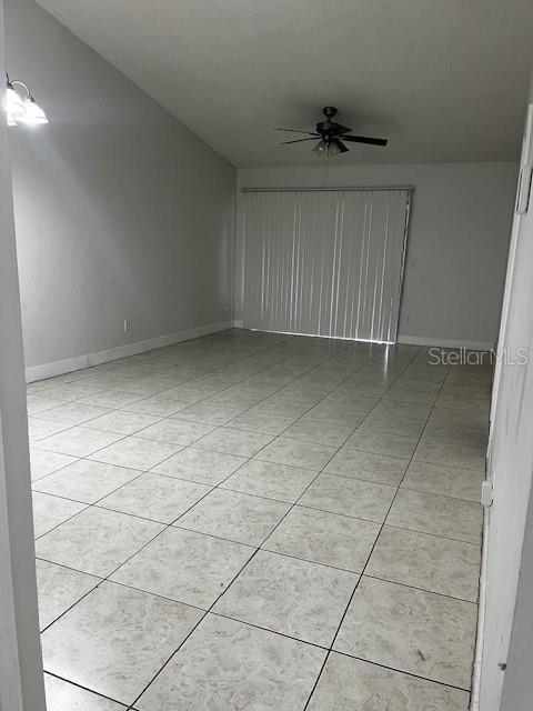 tiled empty room featuring ceiling fan