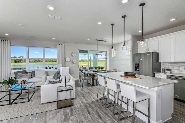 kitchen featuring hanging light fixtures, a kitchen island, white cabinets, appliances with stainless steel finishes, and a water view