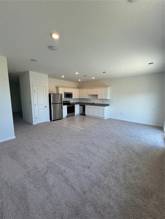 unfurnished living room with a textured ceiling and light carpet