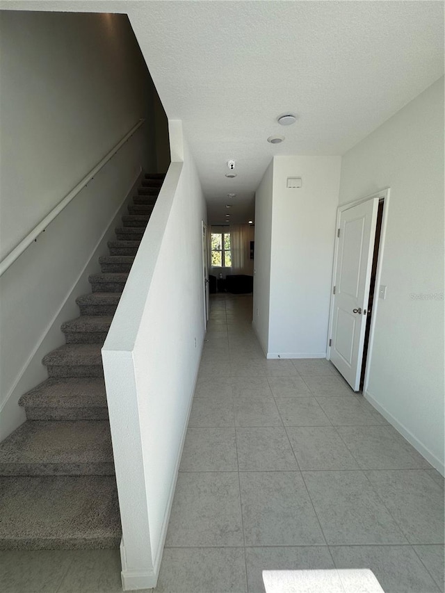 staircase featuring a textured ceiling