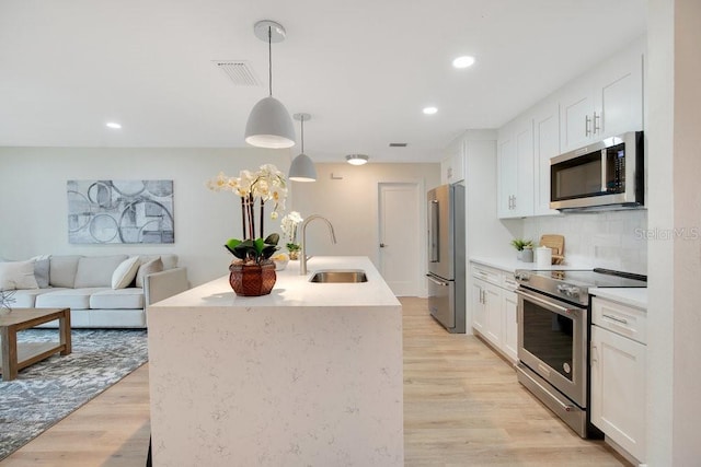 kitchen featuring sink, decorative light fixtures, white cabinets, tasteful backsplash, and appliances with stainless steel finishes