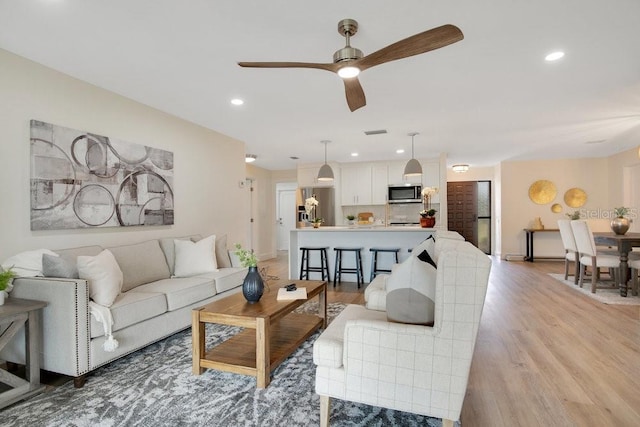 living room with ceiling fan and light wood-type flooring